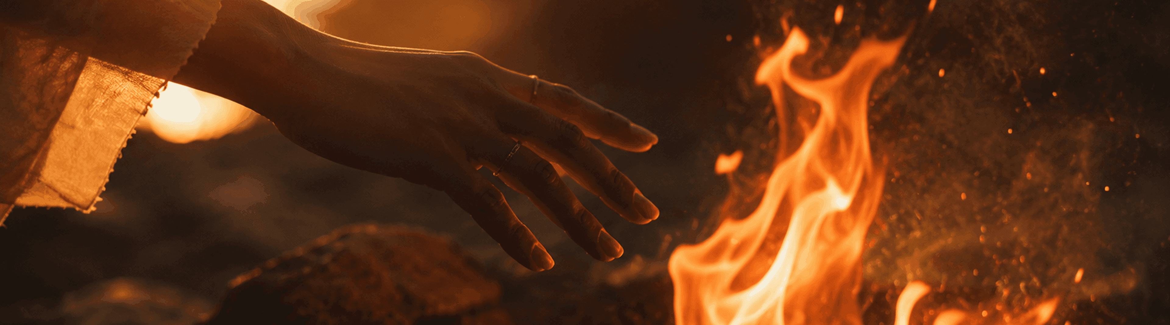 Photo - A hand reaching toward bright flames.